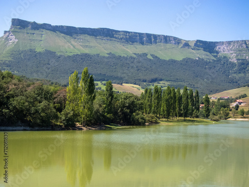 Fototapeta Naklejka Na Ścianę i Meble -  Panoramic view of the Maroño reservoir in Vitoria with a very high flow surrounded by trees, mountains and lots of vegetation on a sunny day in Alava.