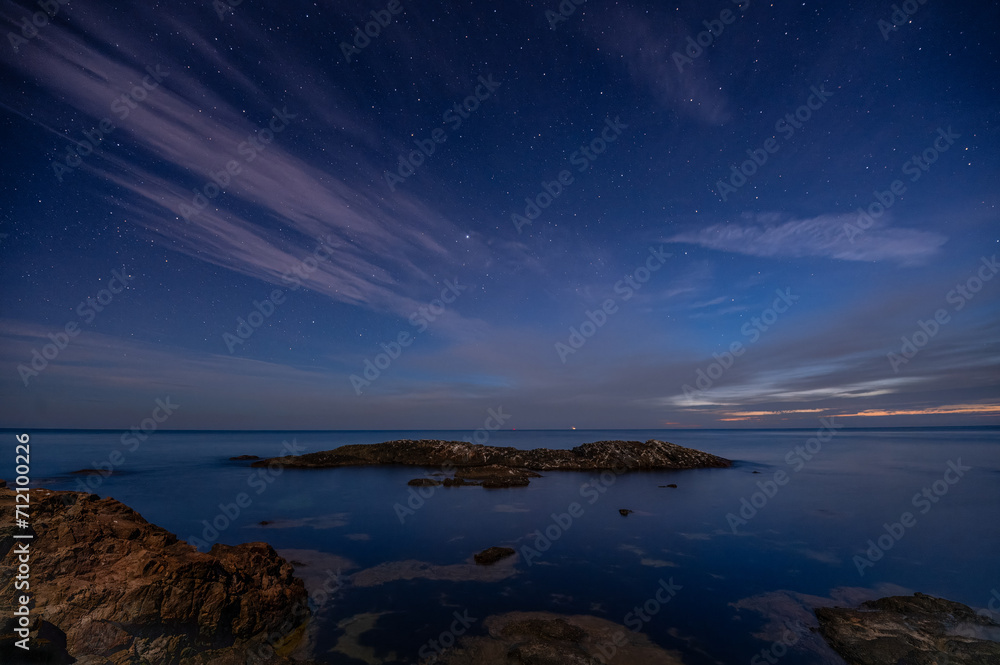 Rocks and stars at sunrise at the sea wide angle