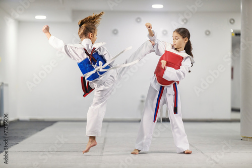 Taekwondo kids in action. Sporty girls wearing doboks practicing combat at martial art school.