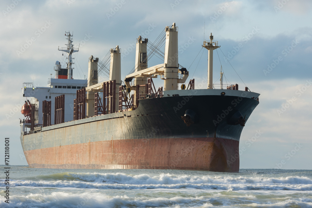 Fototapeta premium A large cargo sea ship sails on the ocean among the waves