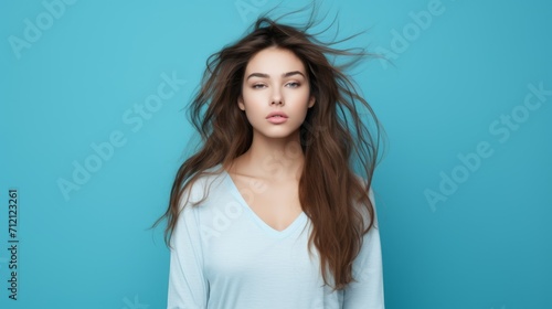 Portrait of a charming woman with long disheveled hair. An overslept girl looks at the camera with displeasure on a blue background. Morning, morning routine, It's time for work. photo