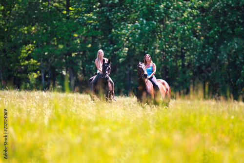 Woman women with horse riding horses on a summer meadow without a saddle.