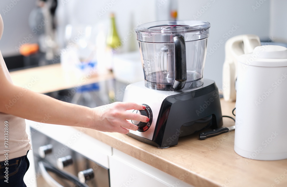 Woman turns on mixer for mixing products. food processor blender concept Woman turns on mixer for mixing products. food processor blender concept
