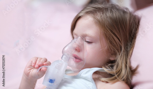 Child with inhaler mask breathing problems with asthma. Healthcare and sick child concept