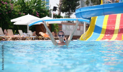 Woman is relaxing in pool and doing aqua aerobics. Happy woman enjoying workout in pool.