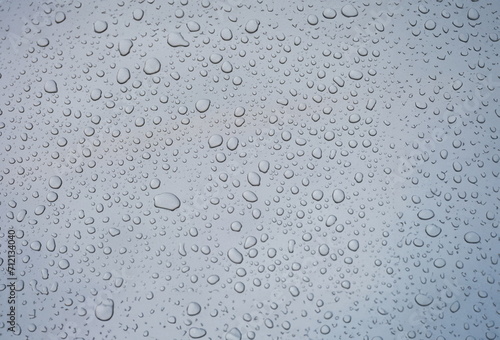 Closeup of raindrops on gray window glass texture background. . Rainy weather concept and natural condensation wallpaper.