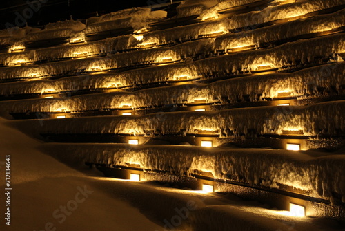 Outdoor concrete amphitheater seats for outdoor theatre venue covered in freshly fallen snow and lit up at night. Concept for snow in unusual places, snowy theatre, outdoor spaces (Vancouver, Canada)