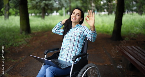 Portrait of woman in wheelchair show ok gesture with hand, work during rehabilitation. Disabled people, recovery, remote job, freelancer, positive concept photo