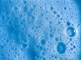In the picture there are blue bubbles with many small and large bubbles together. The surface of the bubbles is white, clumped together and grouped together in white groups with blue bubbles.