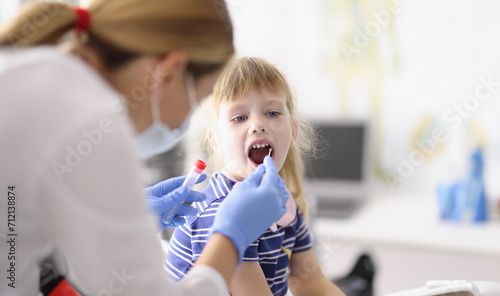 Portrait of laboratory assistant in protective suit takes swab from childs throat, procedure at home, lab test for coronavirus. Quarantine, covid concept