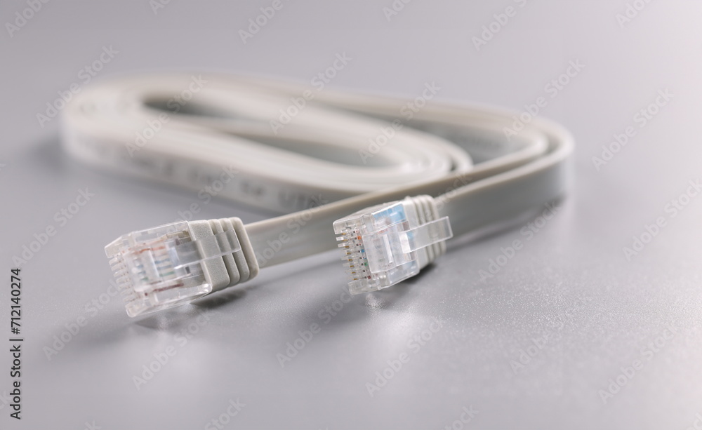 Close-up of white internet connectors placed on grey surface, cable with plastic clip at tip. Internet and telecommunications, modern technology concept Close-up of white internet connectors placed on grey surface, cable with plastic clip at tip. Internet and telecommunications, modern technology concept