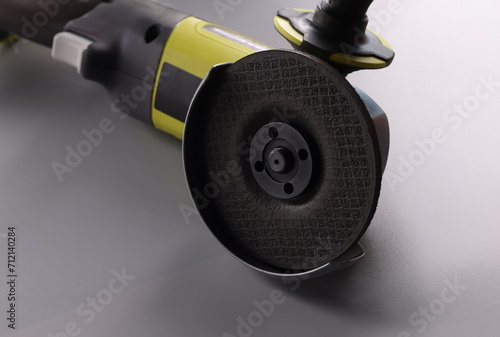 Close-up of electrical saw, grinder with nozzle on grey surface, detailed picture of powerful circular saw tool for construction works. Carpentry concept photo