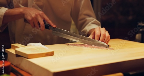 Hands, food and chef cutting sushi in restaurant for traditional Japanese cuisine or dish closeup. Kitchen, cooking seafood for preparation and person working with gourmet meal recipe ingredients