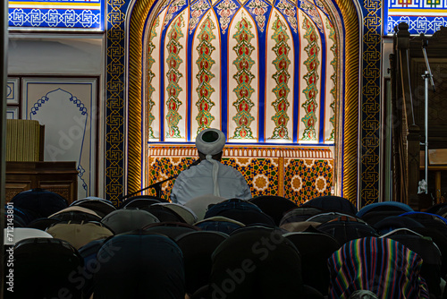 People in a Mosque. Muslims kneeling and bowing down while offering prayers during the Muslim festival of Eid. imam reads a prayer