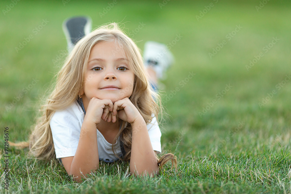 Happy little girl lying on grass and smiling. Perfect for innocence and joy of childhood concept. Ideal for use in advertisements, blog or any content related to children, nature. High quality photo Happy little girl lying on grass and smiling. Perfect for innocence and joy of childhood concept. Ideal for use in advertisements, blog or any content related to children, nature. High quality photo