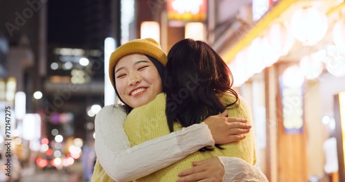 Woman, friends and hug in Japanese city or happy reunion for party night, adventure or Tokyo. Female people, embrace and dark or bokeh on street with light or international travel, journey or evening photo