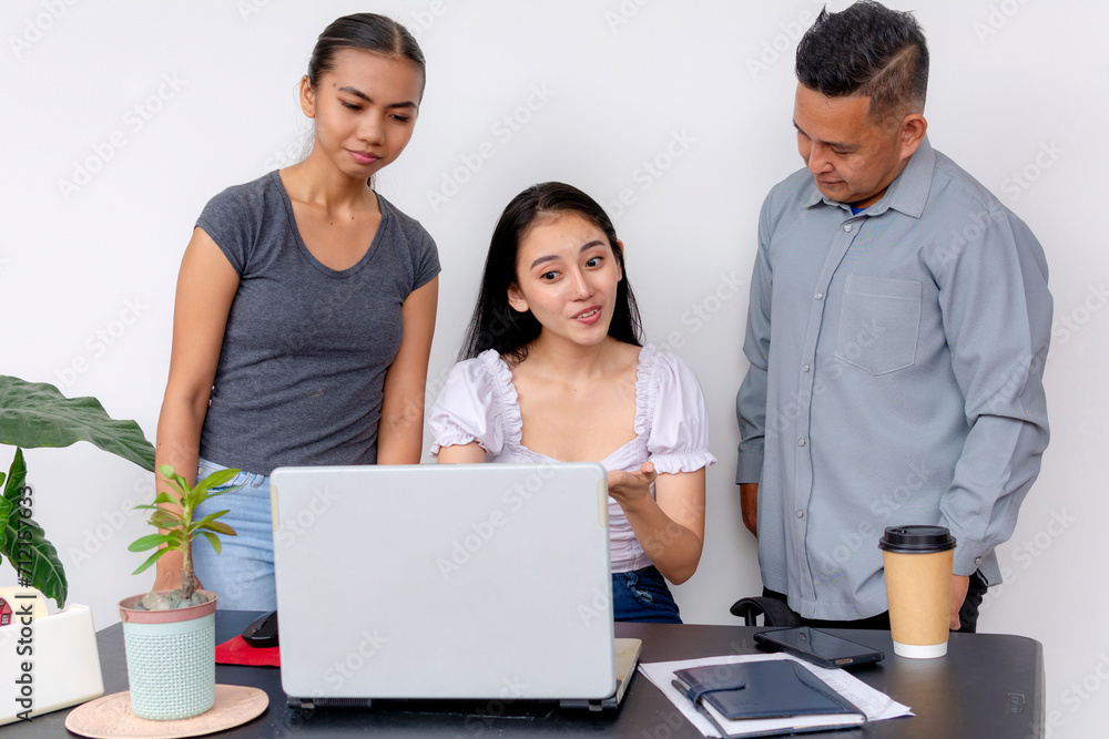 Three colleagues collaborate using a laptop at the office, depicting teamwork, diversity, and a professional setting. Three colleagues collaborate using a laptop at the office, depicting teamwork, diversity, and a professional setting.