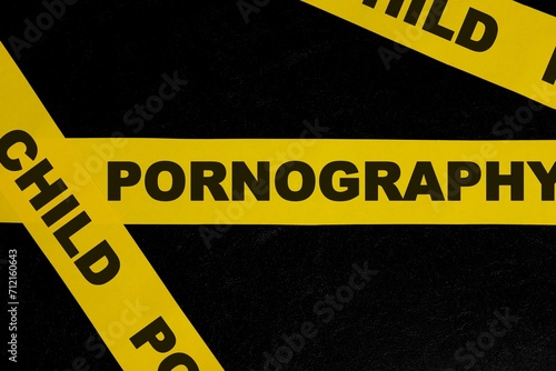 Child pornography caution and warning concept. Yellow barricade tape with word in dark black background.