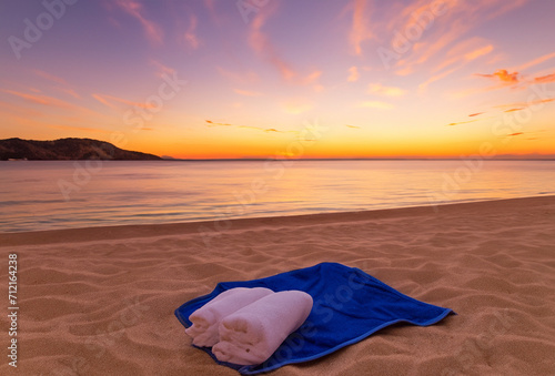 a towel in the sand on a beach at sunset