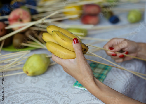 Making process of bouquet of fruits, unusual original gift for lover.  Hand holding a banana for a beautiful fruit bouquet. 