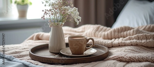 a tray containing coffee and a flower arrangement on top of a bed photo