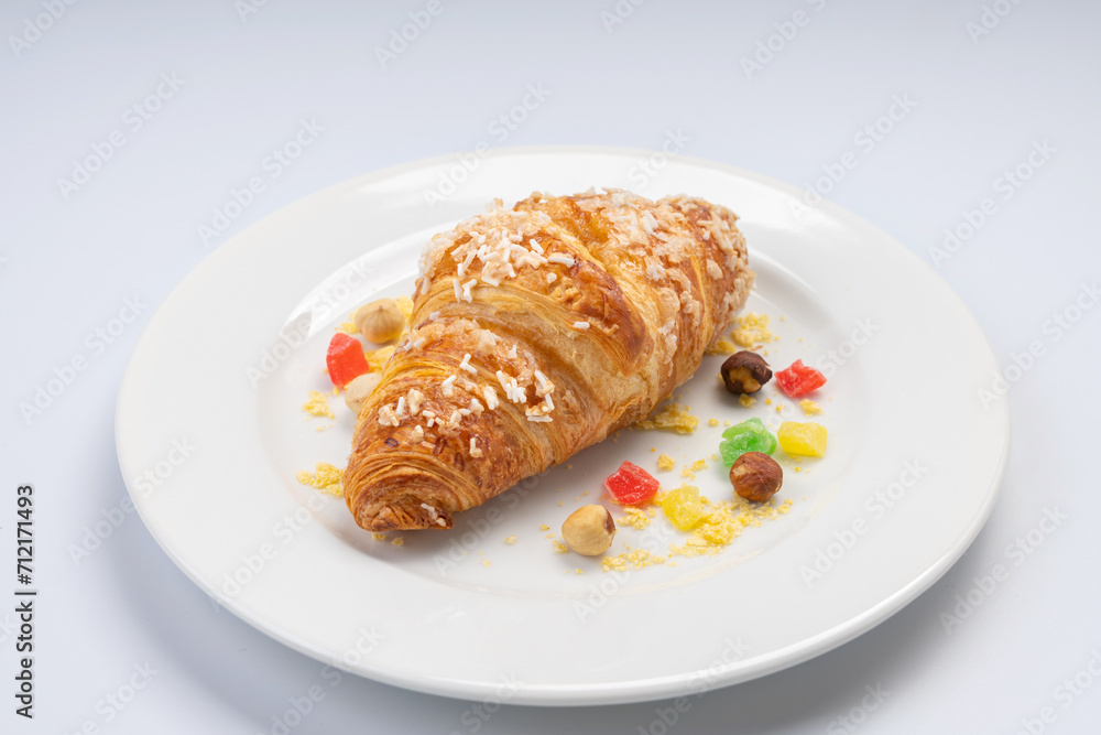 Breakfast. Croissant, seeds and dried fruits on a white plate and a white background Breakfast. Croissant, seeds and dried fruits on a white plate and a white background