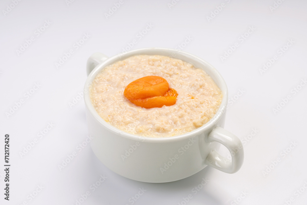 Breakfast. Oatmeal porridge with apricot on a white plate and a white background Breakfast. Oatmeal porridge with apricot on a white plate and a white background