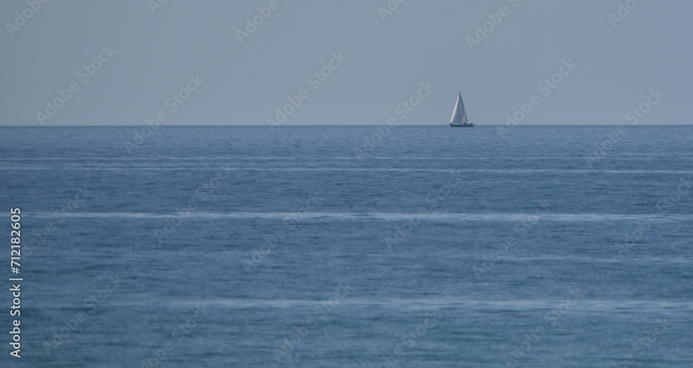 a sailing yacht sails on the horizon at sea