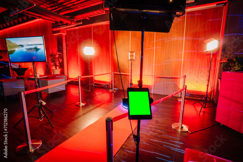 Obraz na plátně 360 spinner photo booth setup with a red carpet, lighting equipment, and a screen in a red-lit event space