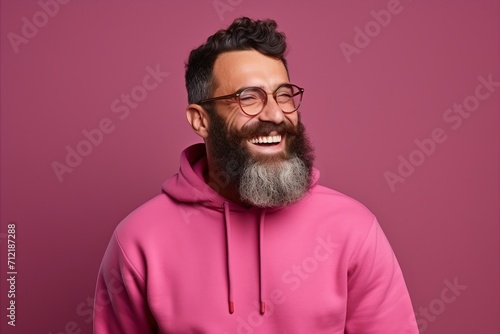 Portrait of a cheerful bearded man in pink hoodie and glasses. © Juan Hernandez