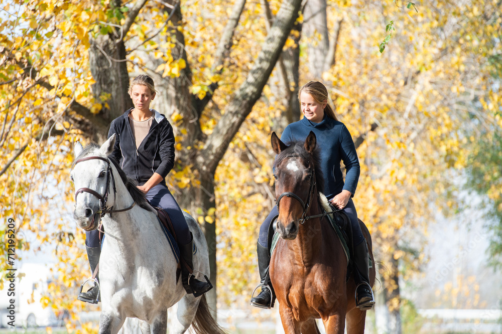 Young girls riding on horseback through the forest Young girls riding on horseback through the forest
