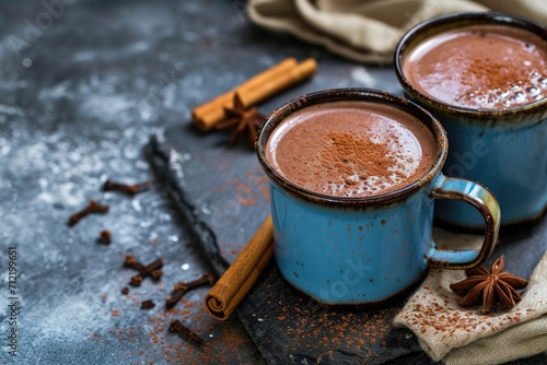 Spicy hot chocolate with cinnamon in an enamel mug on a slate stone or concrete background