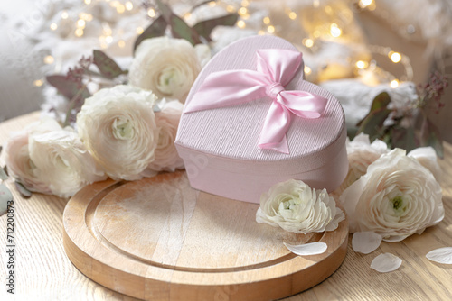 Composition with a pink heart-shaped gift box and flowers.