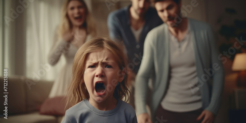 A distressed young girl screaming with a blurred family arguing in the background, capturing a moment of family conflict or tantrum. photo