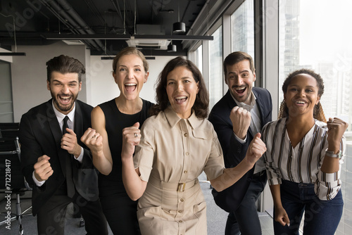 Excited group of business colleagues celebrating team success, making winner yeas gestures, looking at camera for portrait, shouting for joy, laughing, having fun, enjoying successful teamwork photo