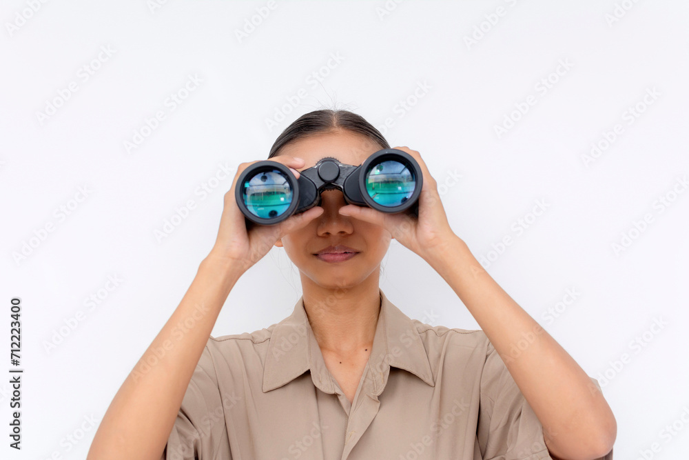 Focused young Filipino woman using binoculars to search or observe, isolated on a white background with copy space.