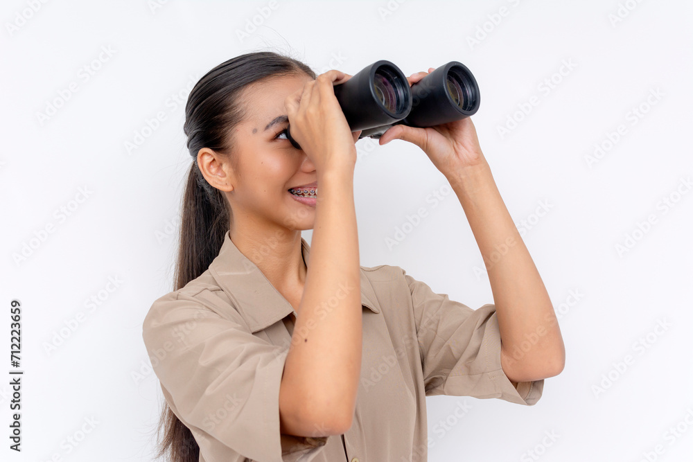 A cheerful young Filipino woman with binoculars, looking into the distance with a smile. A cheerful young Filipino woman with binoculars, looking into the distance with a smile.