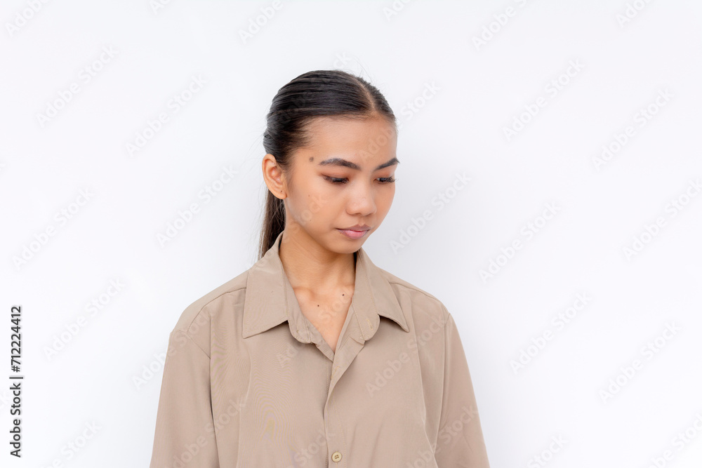 Portrait of a calm young Filipino woman in casual attire looking down. Isolated against a plain backdrop. Portrait of a calm young Filipino woman in casual attire looking down. Isolated against a plain backdrop.