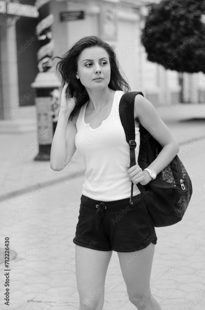 a woman in a white t-shirt and black shorts walks down a city street