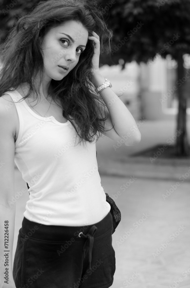 a woman in a white t-shirt and black shorts walks down a city street a woman in a white t-shirt and black shorts walks down a city street