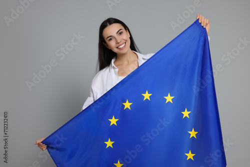 Woman holding European Union flag on light grey background