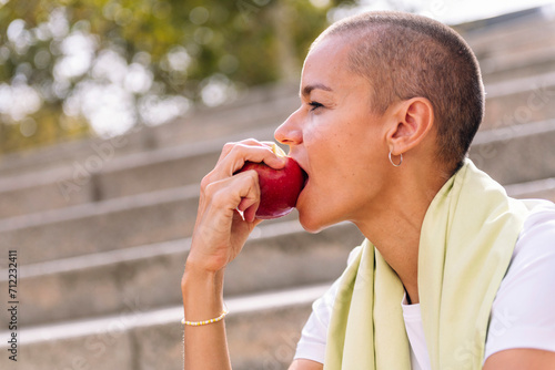 young sports woman rests eating an apple after a hard workout, concept of healthy and active lifestyle, copy space for text