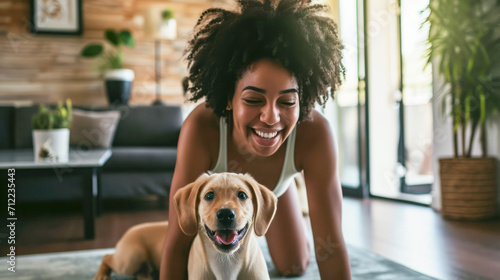 A smiling African American woman exercising on a mat and a puppy dog disturbing her. Modern apartment background. 
