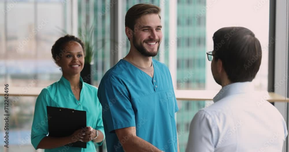 Happy confident doctor colleagues shaking hands in clinic space, speaking, smiling, expressing gratitude, discussing successful cooperation. Practitioner giving handshake to surgeon, thanking coworker Happy confident doctor colleagues shaking hands in clinic space, speaking, smiling, expressing gratitude, discussing successful cooperation. Practitioner giving handshake to surgeon, thanking coworker