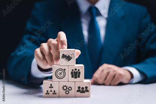 Credibility, reputation and trust concept, Businessman stack wooden block with human and shaking hands icon for business team making. photo