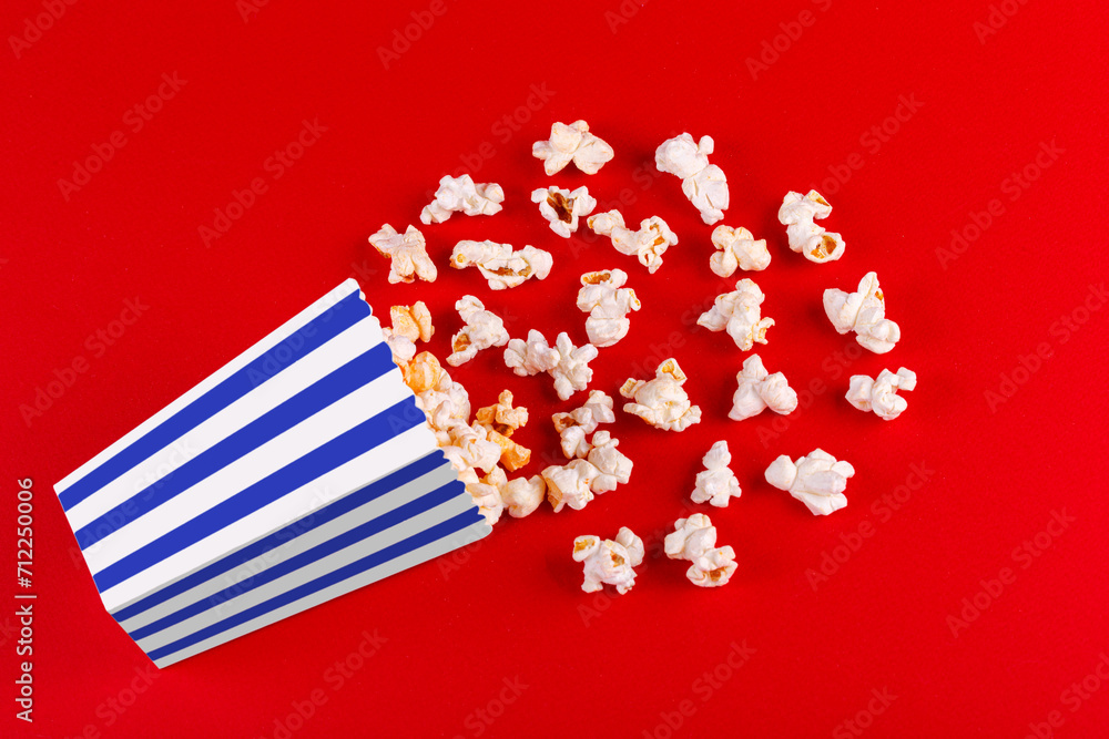 Obraz premium box with popcorn striped in different colors on a red background