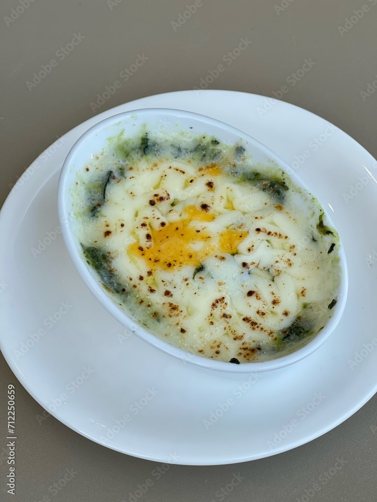 Baked spinach with cheese in a white cup on white backaround. Baked spinach with cheese in a white cup on white backaround.