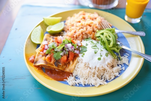 individual serving of enchilada with a side of rice and beans