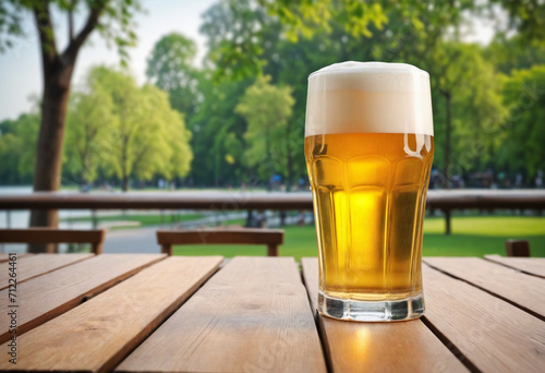 Closeup of beer in glass on wooden table with blurred city park in background, natural setting.