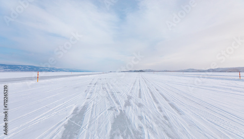 Beautiful winter landscape with car tire tracks (trail) in fresh snow - Baikal Lake, Siberia © muratart